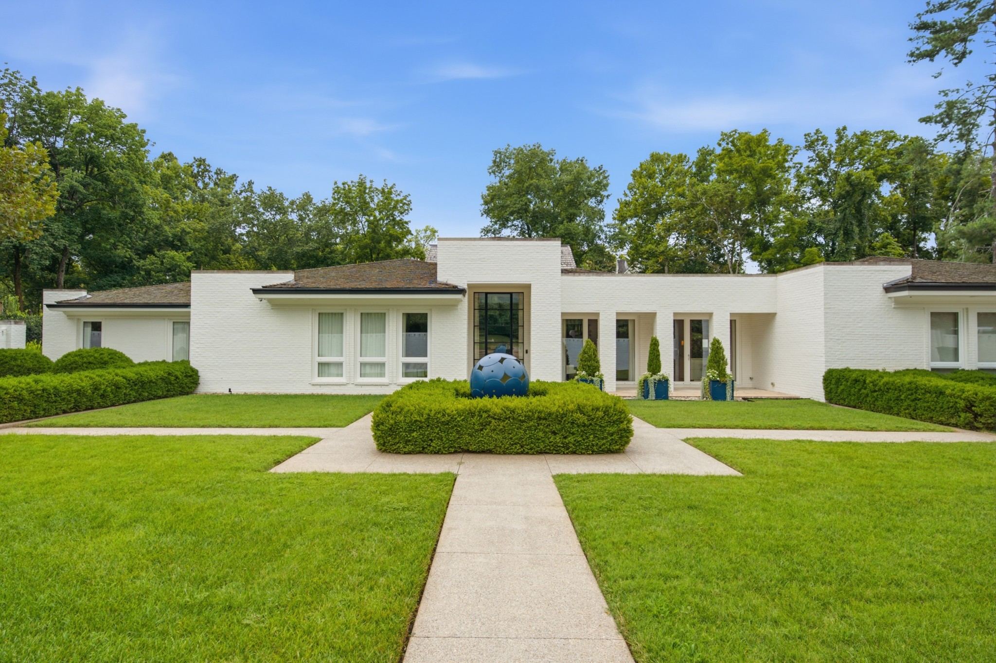 Front exterior of 109 Westhampton Place, a white one level home with a long walk through a formal lawn and boxwoods, one of the Belle Meade homes for sale in Nashville