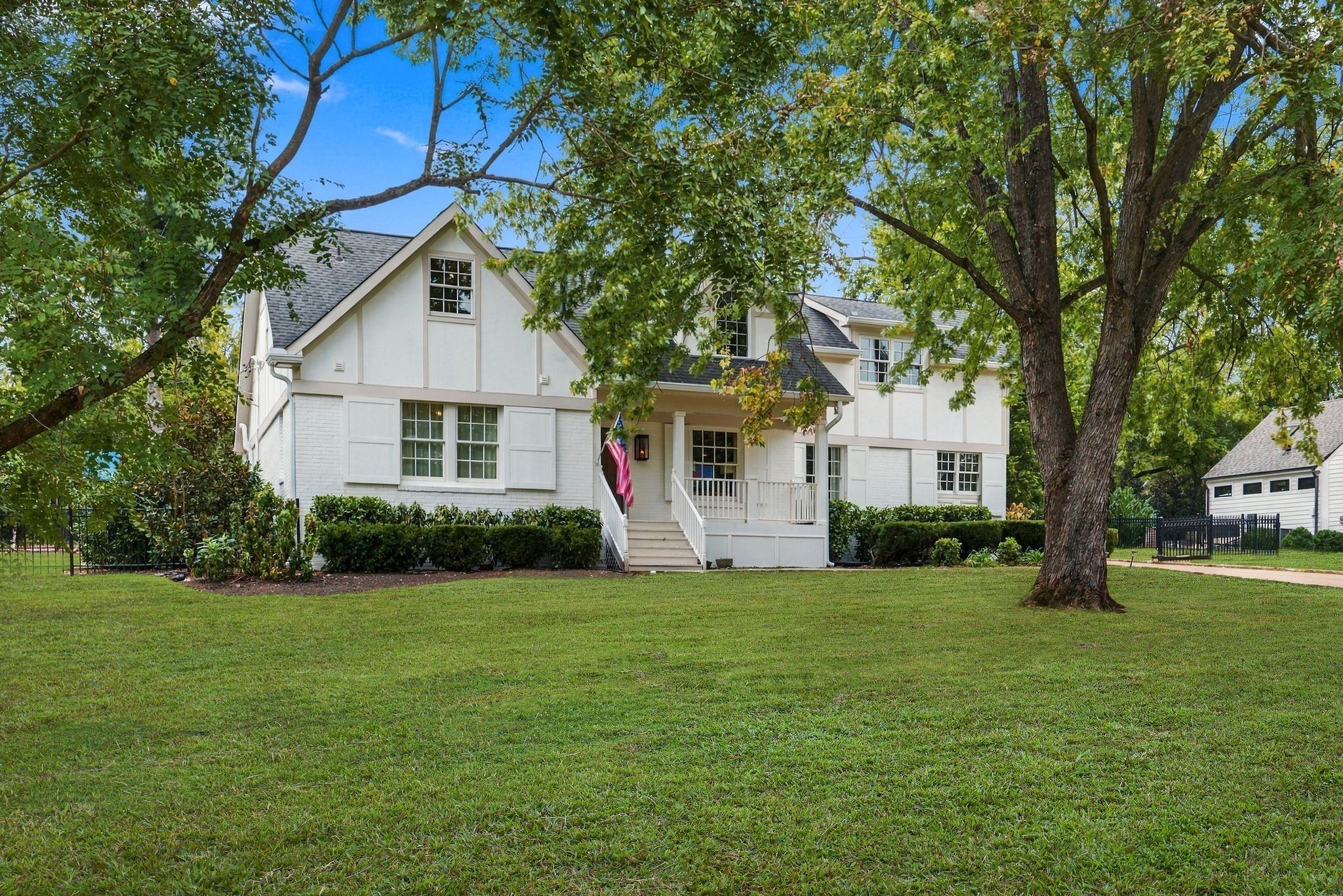Front exterior of 200 Leake Avenue, a white two story home with a front porch, a wide front lawn and large shade trees