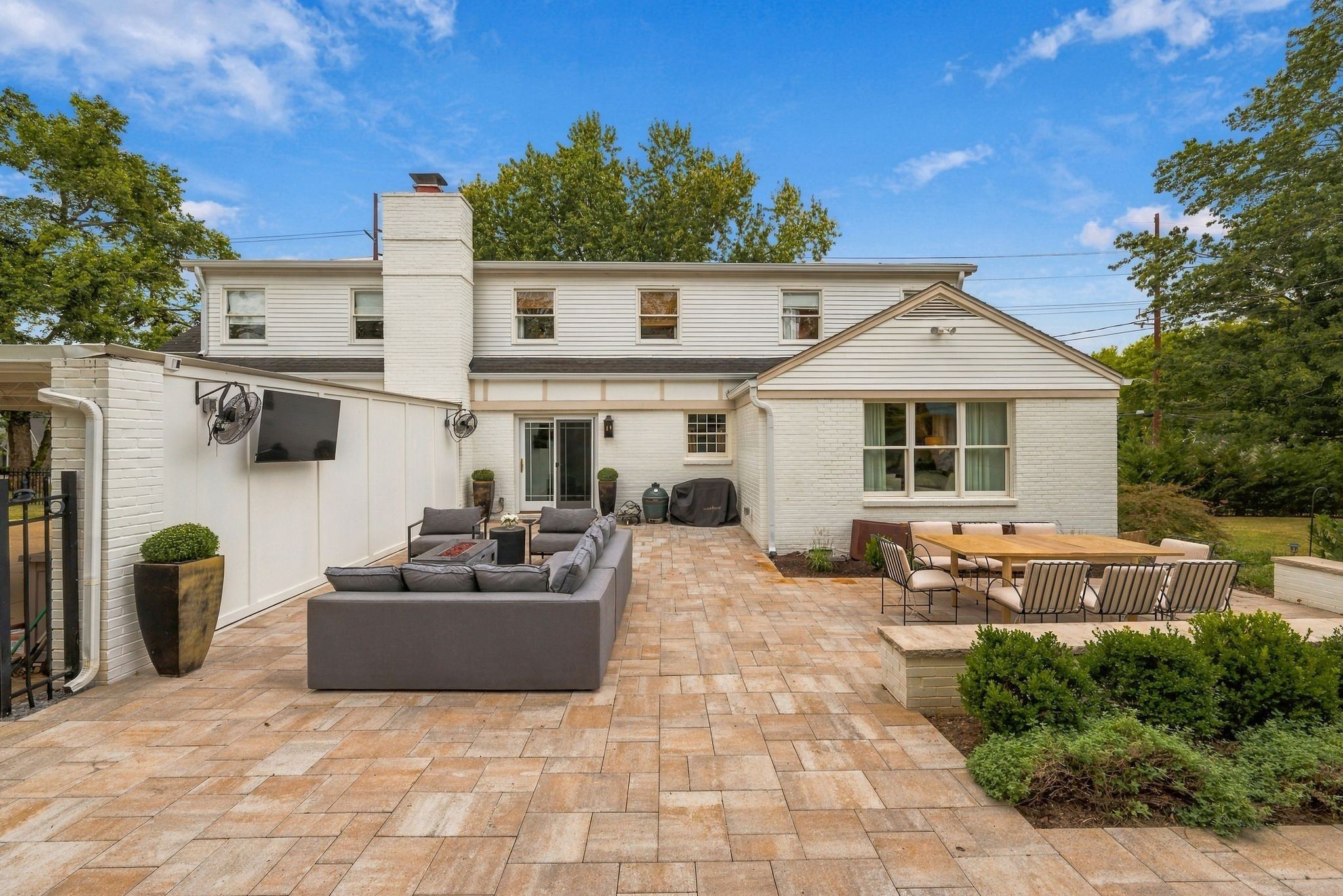 Stone patio with outdoor seating behind 200 Leake Avenue, a white home with a level back yard in Belle Meade Nashville