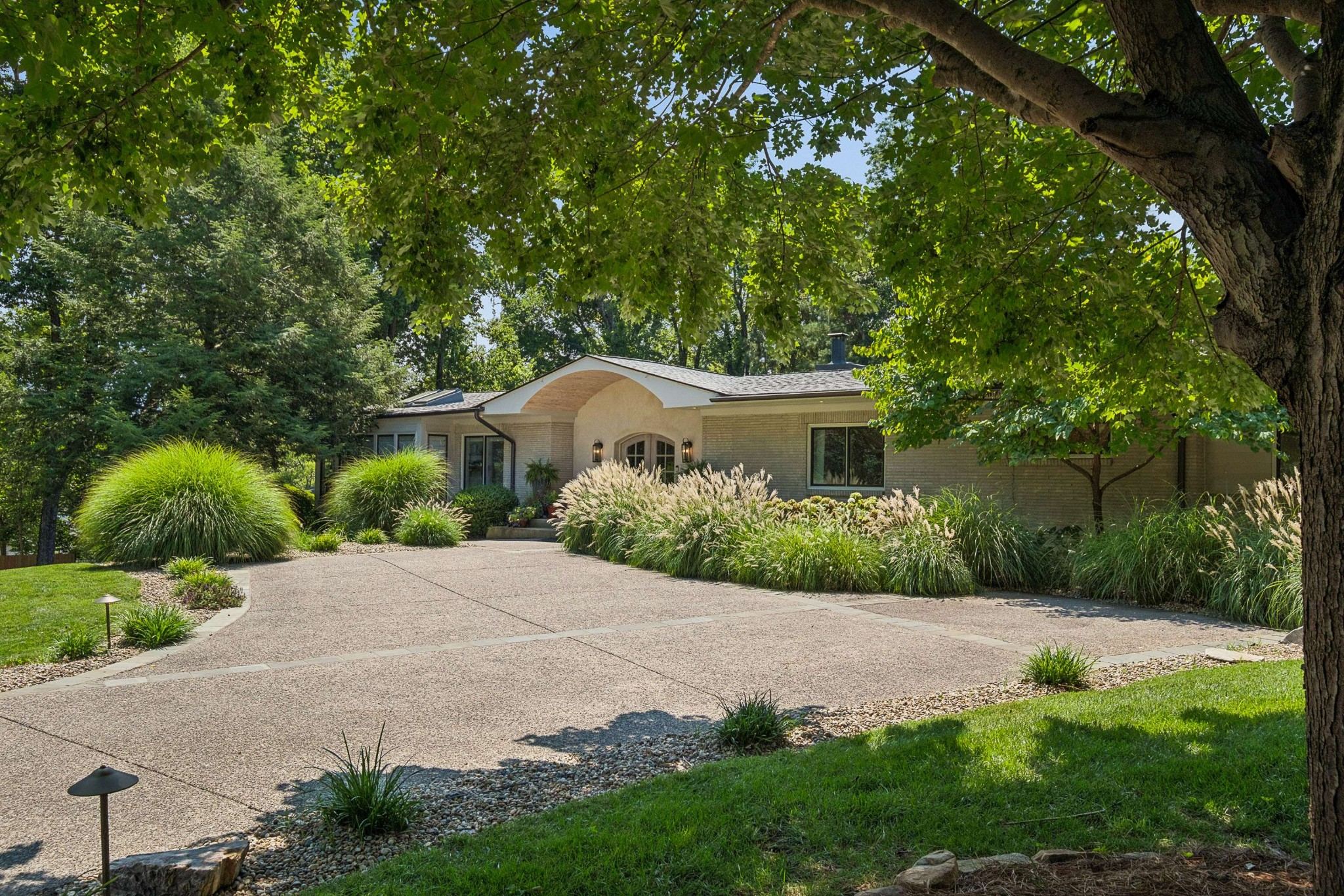 Front exterior of 4301 Lillywood Road, a low one story home set back at the end of a long driveway behind mature trees and landscaped beds