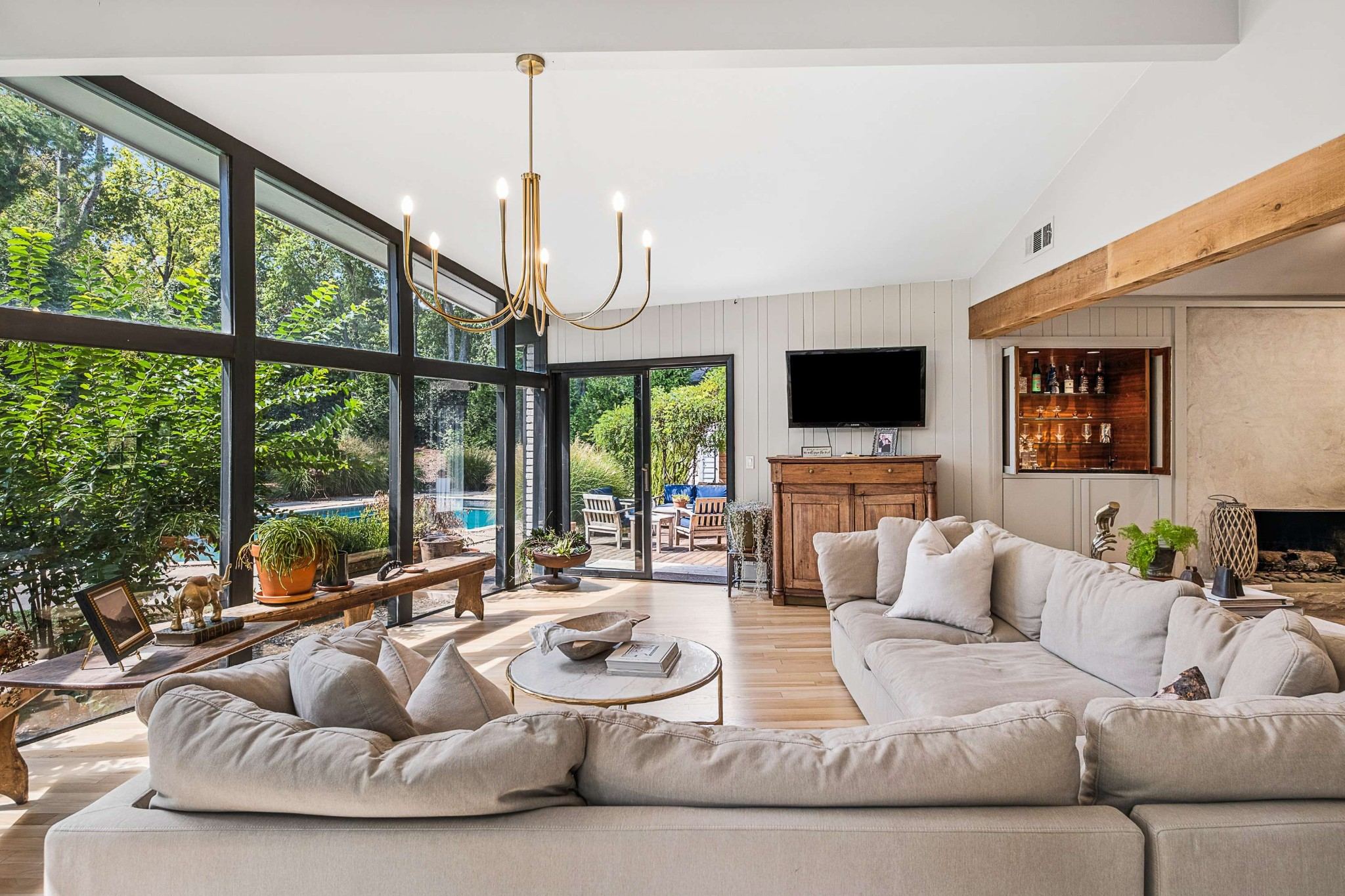 Living room with a wall of floor to ceiling glass, a fireplace, light wood floors and a sectional sofa at 4301 Lillywood Road in Belle Meade Nashville