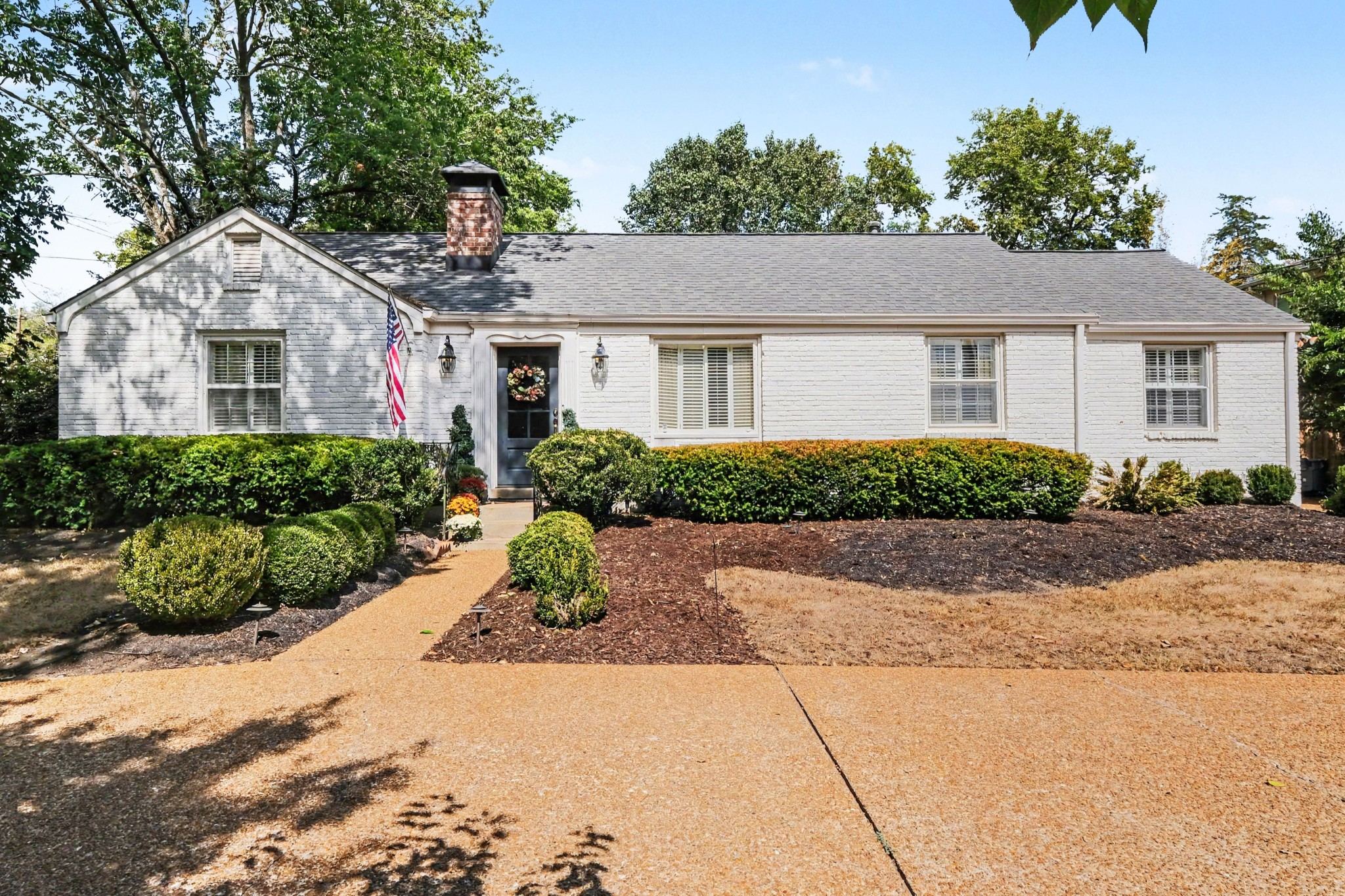 Front exterior of 4306 Harding Place, a white one story home with a circle driveway, shrubs and mature trees